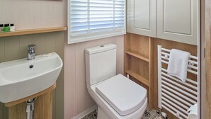 A bathroom with a sink, toilet, and a towel rack. - Modern, contemporary holiday home facing the sea. (Lendalfoot)