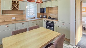 A compact kitchen with a wooden countertop, a dining table, and a built-in oven. - Modern, contemporary holiday home facing the sea. (Lendalfoot)