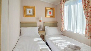 A double room with two beds, a nightstand, a lamp, and two framed pictures on the wall. - Modern, contemporary holiday home facing the sea. (Lendalfoot)