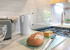 Una cocina con un pan, una caja de mantequilla Anchor y una tetera sobre la encimera.