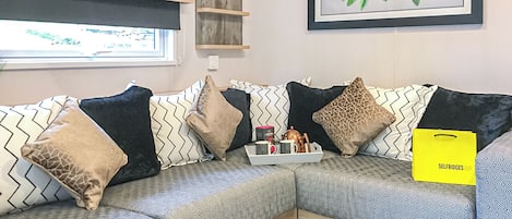 Ein modernes Wohnzimmer mit einem Ecksofa, Zierkissen, einem gerahmten Kunstwerk und einer gelben Tasche auf dem Sofa.
