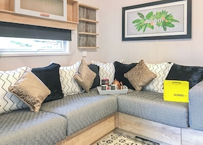 Una sala moderna con un sofá modular, cojines decorativos, una obra de arte enmarcada y un bolso amarillo sobre el sofá.