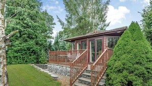 Eine Holzhütte mit einer Steintreppe, die zu einer Terrasse führt, umgeben von dichtem Wald.