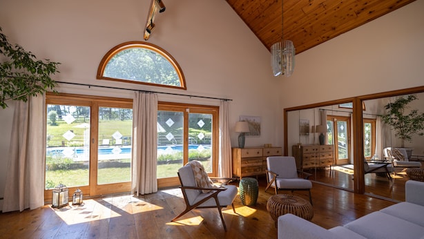 Un salón espacioso con piso de madera, un gran ventanal de arco y vistas a un jardín.