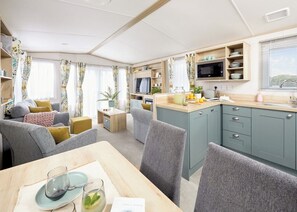 A compact living space with a kitchenette, a dining area, and a seating area with a sofa and chairs.