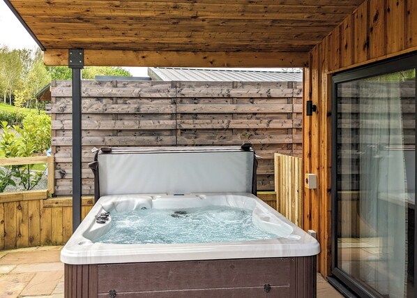 A hot tub under a wooden pergola with a wooden fence in the background. - A magnificent bespoke lodge perfect for a family escape with pets. (Gledrid, Chirk)