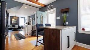Een moderne keuken met een houten keukeneiland, donkerblauwe wanden en een eethoek met een blauwe stoel.