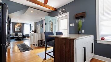 Una cocina moderna con una isla de madera, paredes azul oscuro y una zona de comedor con una silla azul.