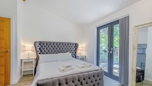 Una camera da letto con una testiera trapuntata, un letto con lenzuola bianche, due comodini con lampade e un grande specchio appeso al muro.