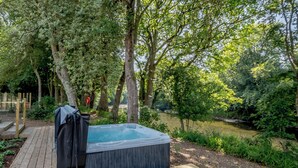Una vasca idromassaggio in un giardino boschivo con un pontile in legno.