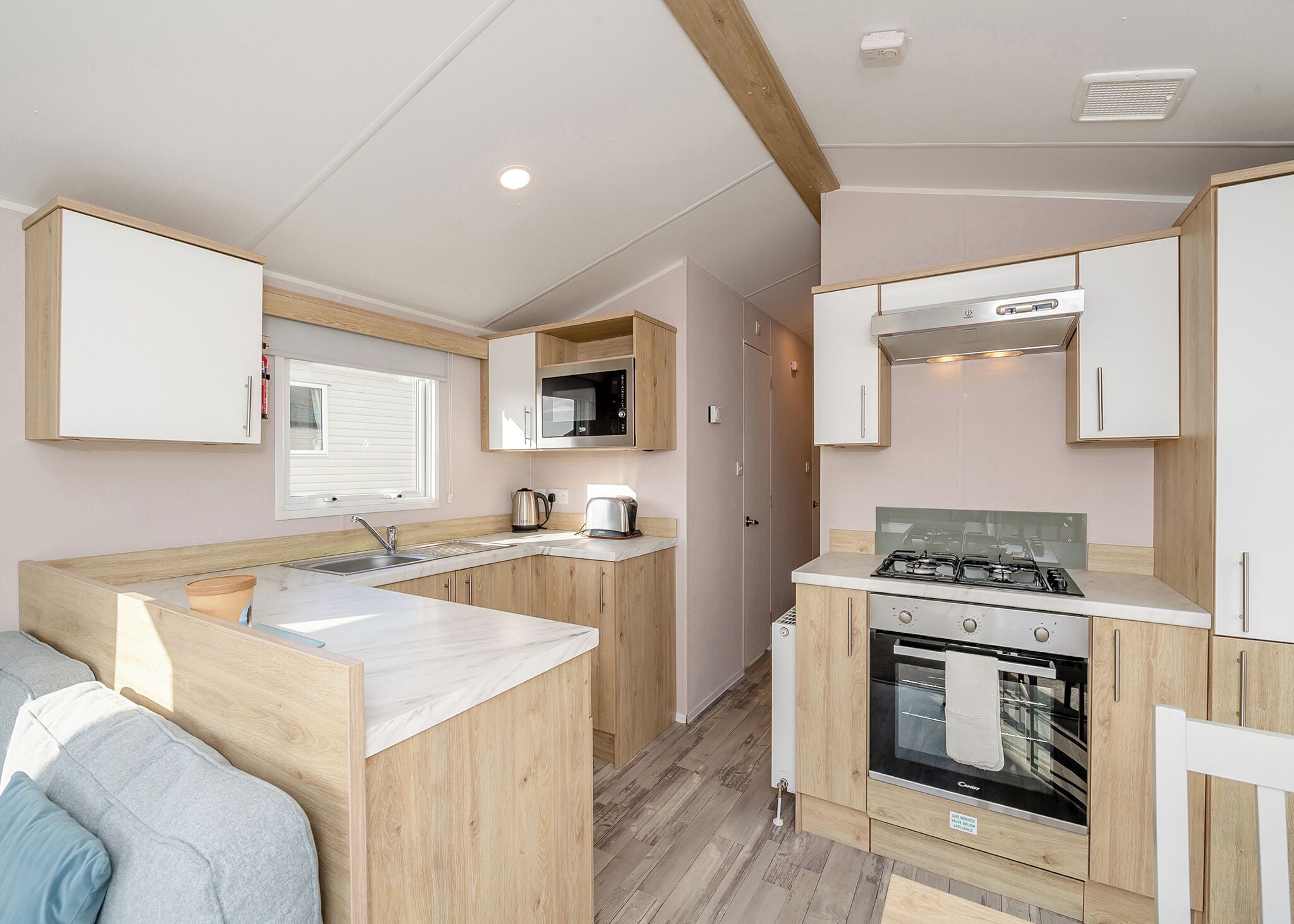 Une cuisine compacte équipée d’un évier, d’une cuisinière, d’un four à micro-ondes et de meubles de rangement en bois.