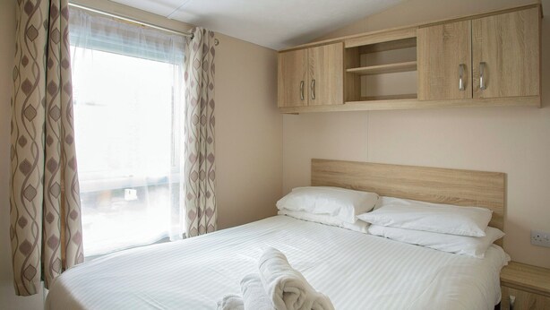 Ein Hotelzimmer mit einem Bett, einem Holzschrank und einem Fenster mit Vorhängen.