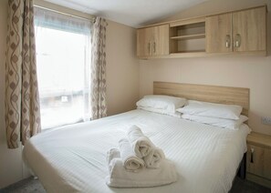 A hotel room with a bed, a wooden wardrobe, and a window with curtains.