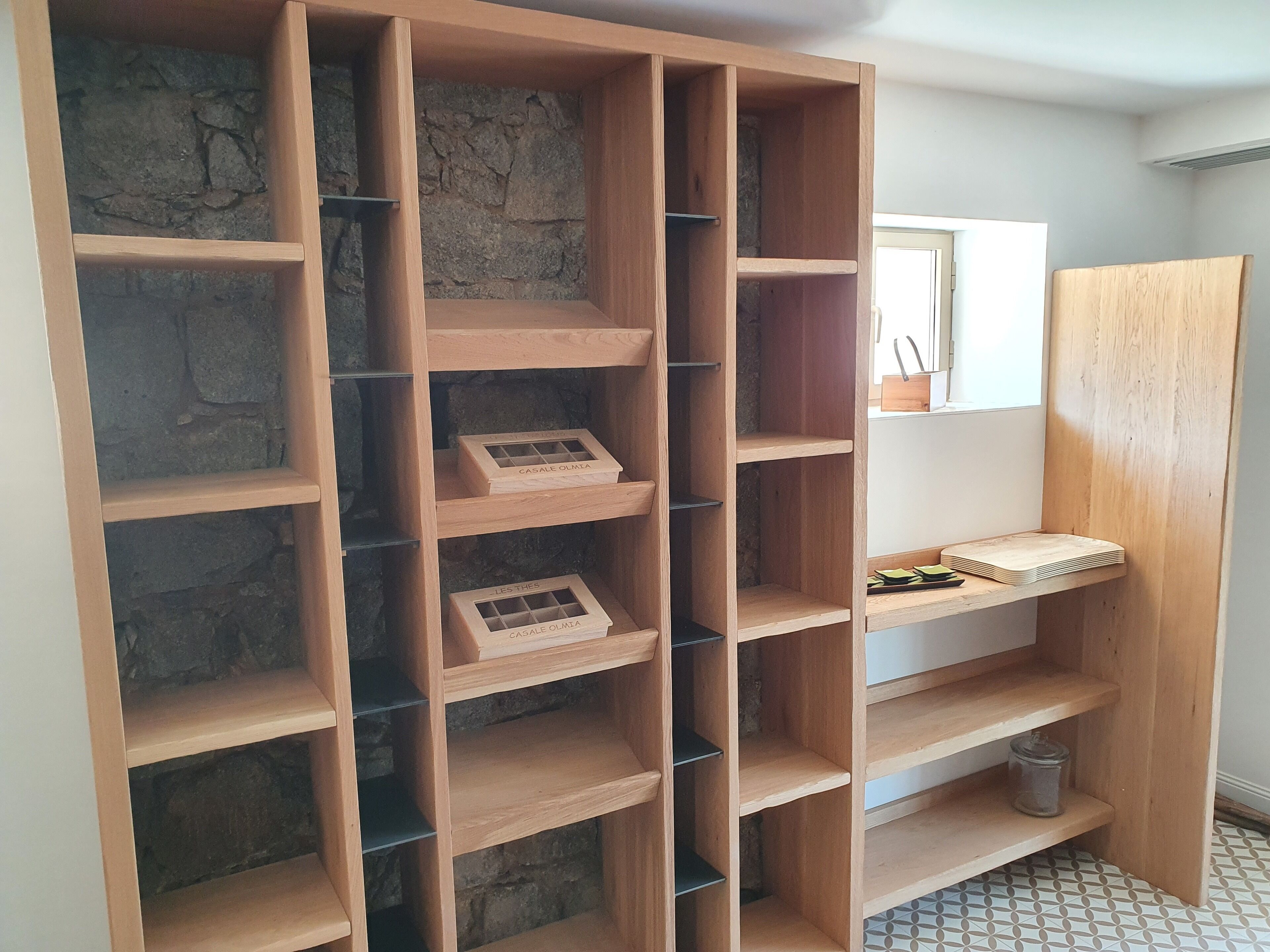 A wooden shelving unit with multiple compartments, some containing boxes labeled "CASALE OLMA."