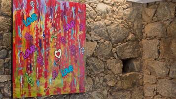 Une peinture abstraite aux couleurs vives, sur laquelle figure le mot « Amour » ainsi que divers mots positifs tels que « Sourire » et « Génial », le tout sur un mur à texture.