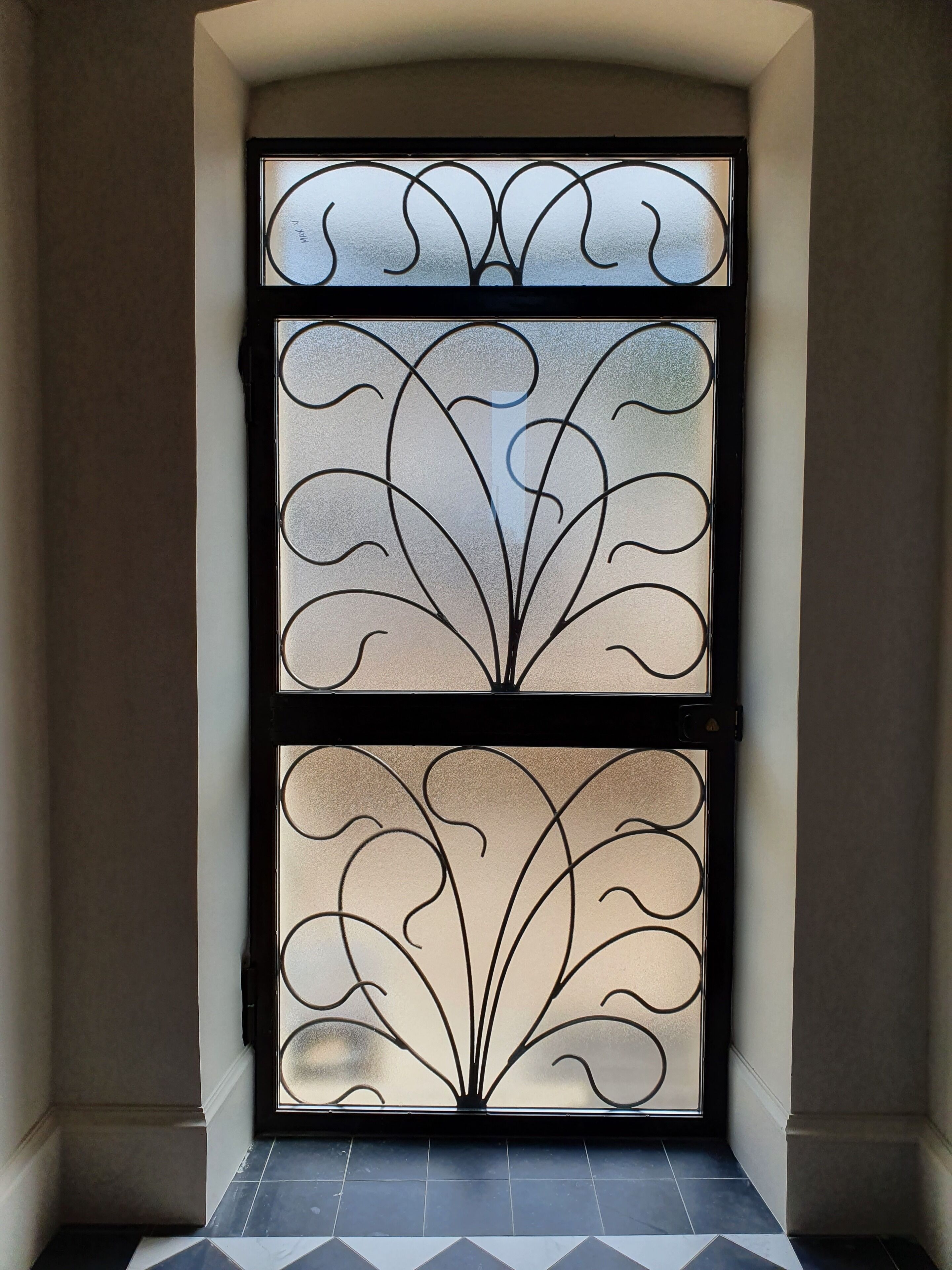 A double door with intricate metal designs and frosted glass panels.