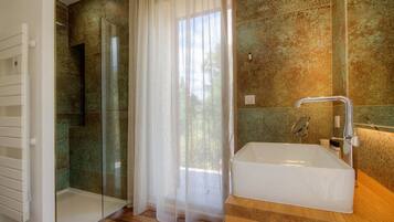 Un baño moderno con mampara de vidrio, una bañera grande y un tocador de madera.