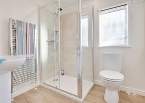 A bathroom with a glass-enclosed shower, a toilet, and a towel rack with striped towels.