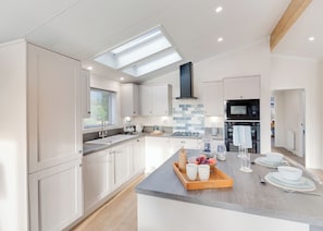 A modern kitchen with skylights, a central island, and a view of the adjacent living area.