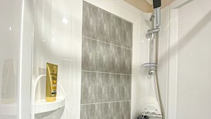 A bathroom with a shower, a white sink, and a bottle of Pantene shampoo. - 2 bedroom accommodation in Snowdonia (Snowdonia)