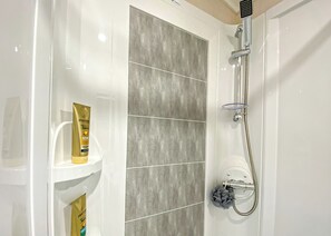 A bathroom with a shower, a white sink, and a bottle of Pantene shampoo. - 2 bedroom accommodation in Snowdonia (Snowdonia)