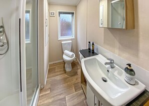 Un baño con ducha, inodoro, lavamanos y ventana.