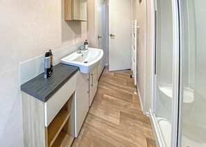 Een badkamer met een wastafel, spiegel en douche.