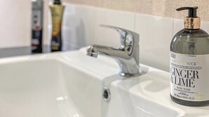 A bathroom sink with a bottle of hand wash soap labeled 'Ginger & Lime' and a faucet. - 2 bedroom accommodation in Snowdonia (Snowdonia)