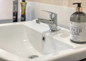 Een wastafel met een handzeepfles met de tekst 'Ginger & Lime' en een kraan.