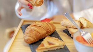 A tray with pastries including a croissant, a slice of pie, and a small bowl of fruit. - Hotel dei Tacchi (Osini)