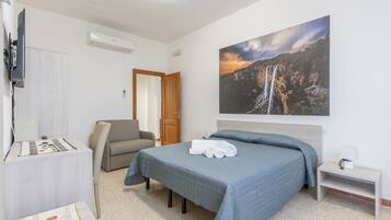 Une chambre d’hôtel équipée d’un lit, d’un bureau, d’une chaise, d’une télévision et d’un tableau représentant une cascade.