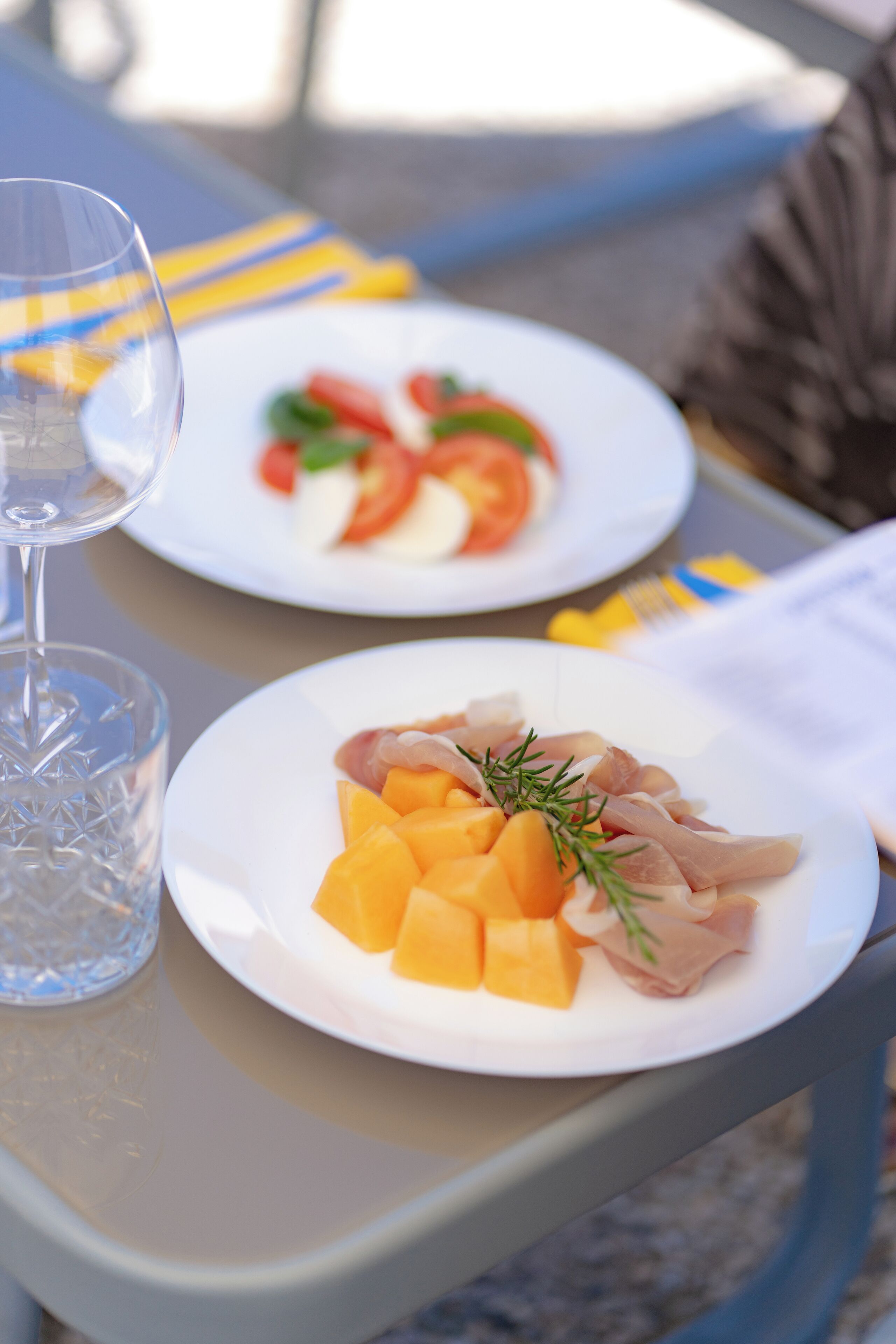 Two plates of food on a table with a glass of water.