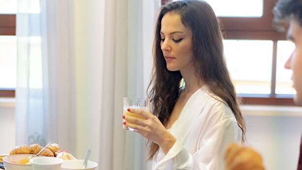 A breakfast setting with a tray of croissants, bowls of fruit, and a glass of orange juice. - Hotel dei Tacchi (Osini)
