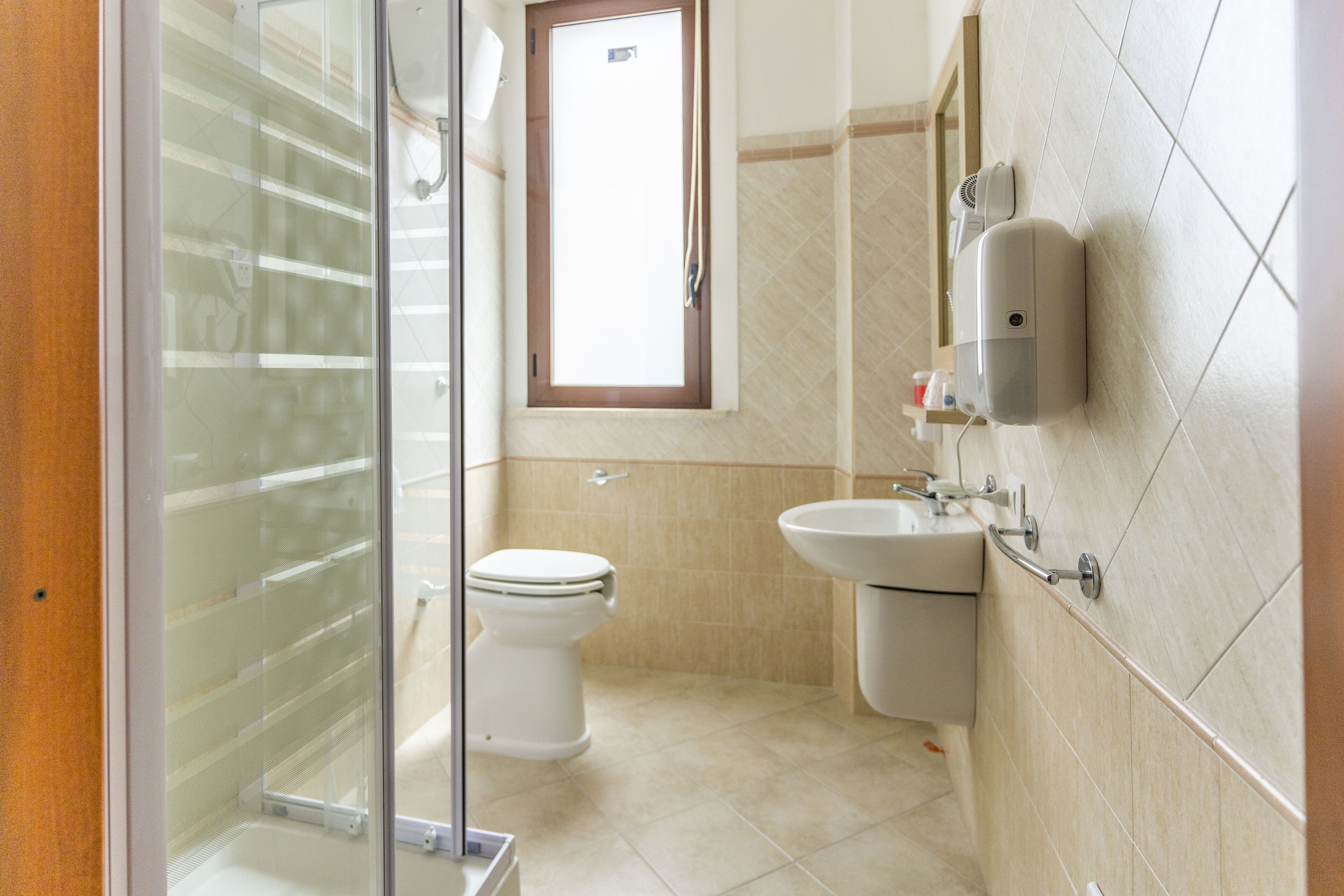 A bathroom with a glass shower enclosure, a toilet, a sink, and a mirror.
