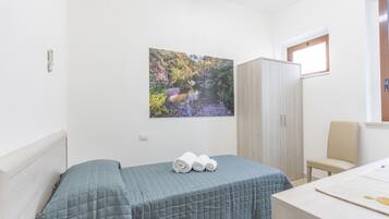 Una camera da letto con un letto, una scrivania, una sedia, un armadio e un quadro che raffigura un paesaggio.