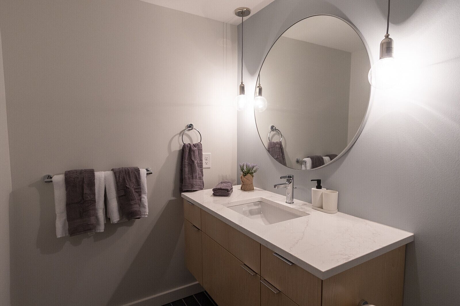 A modern bathroom with a large mirror, a sink, and two towel racks.