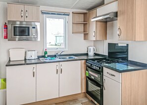 Una kitchenette pequeña equipada con microondas, tostadora, pileta, cocina y horno.