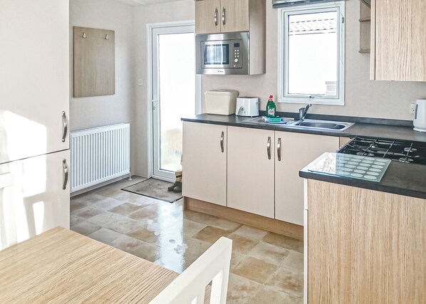 A kitchen with a microwave, stove, sink, and cabinets.