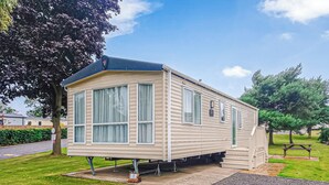 A single-story mobile home with a covered porch, large windows, and a small attached garage. - York Standard Caravan (Thirsk)