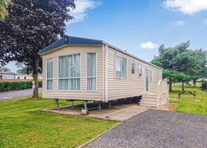 Une maison mobile de plain-pied dotée d’un porche couvert, de grandes fenêtres et d’un petit garage attenant.
