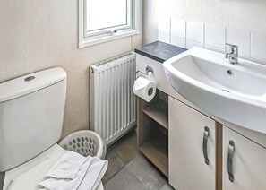 Une salle de bain équipée de toilettes, d’un radiateur, d’un lavabo et d’une fenêtre.