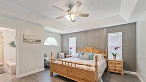 A bedroom with a wooden bed, a ceiling fan, and a view of the outside through a window. - Completely renovated! Private 3/2/2 heated pool home in Port St Lucie FL! (Port St. Lucie)