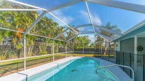 A swimming pool with a glass enclosure, surrounded by a fence and palm trees. - Completely renovated! Private 3/2/2 heated pool home in Port St Lucie FL! (Port St. Lucie)