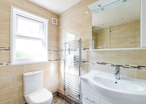 A bathroom with a toilet, a sink, a shower, and a window.