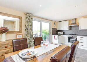 A modern kitchen with white cabinets, a microwave, and an oven. There is a dining table with a white placemat and a plate of food.