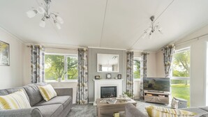Una sala de estar con chimenea, sofá, mesa de centro y televisor.