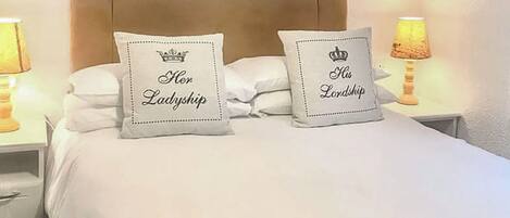 Ein Bett mit zwei Kissen, jedes mit einer Krone und Text.