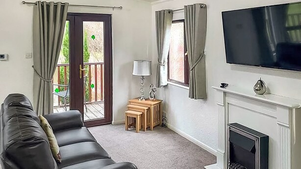 Ein Wohnzimmer mit einer Couch, einem Fernseher, einem Kamin und einer Tür zu einem Außenbereich.