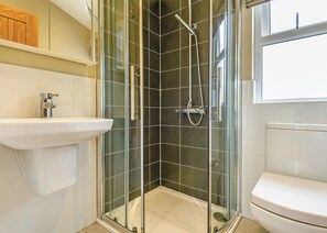 A bathroom with a glass-enclosed shower, a white sink, and a toilet.