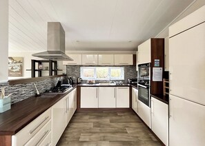Una cocina moderna con una isla central, electrodomésticos de acero inoxidable y un ventanal que proporciona luz natural.
